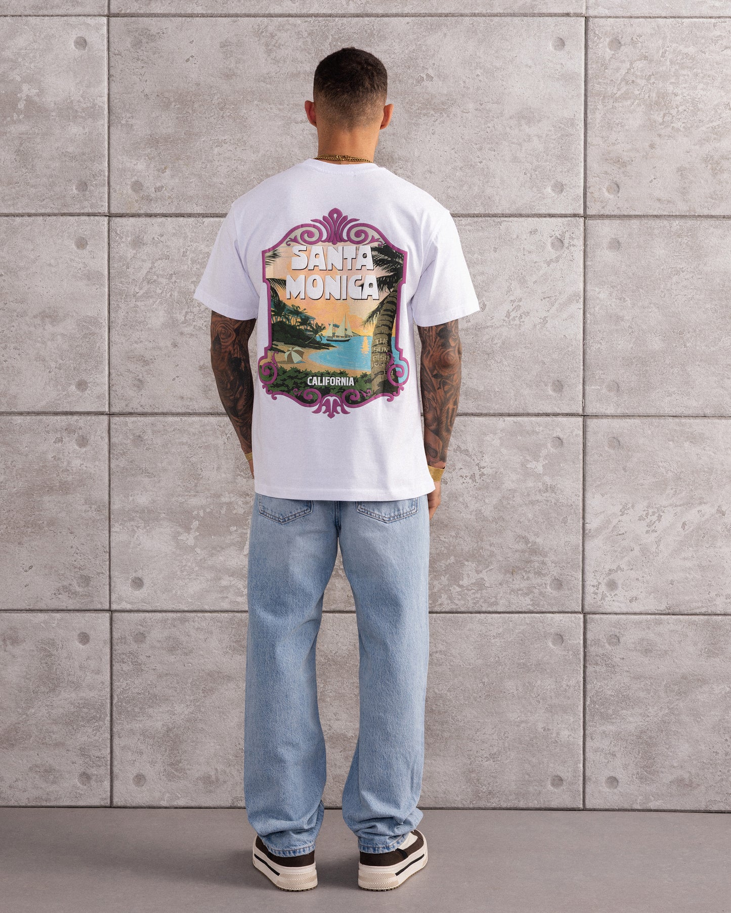 T-shirt blanc oversize avec grand visuel rétro Santa Monica California imprimé dans le dos, ambiance carte postale californienne.